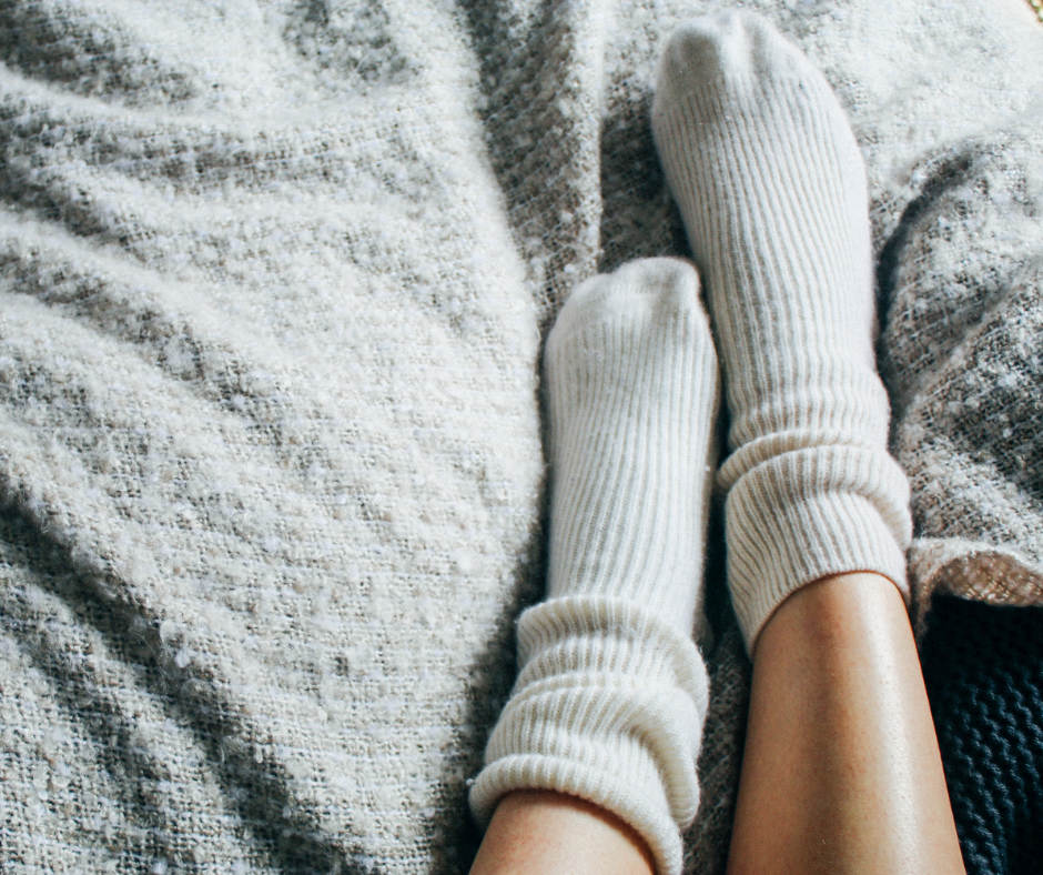 feet wearing warm socks on top of a blanket